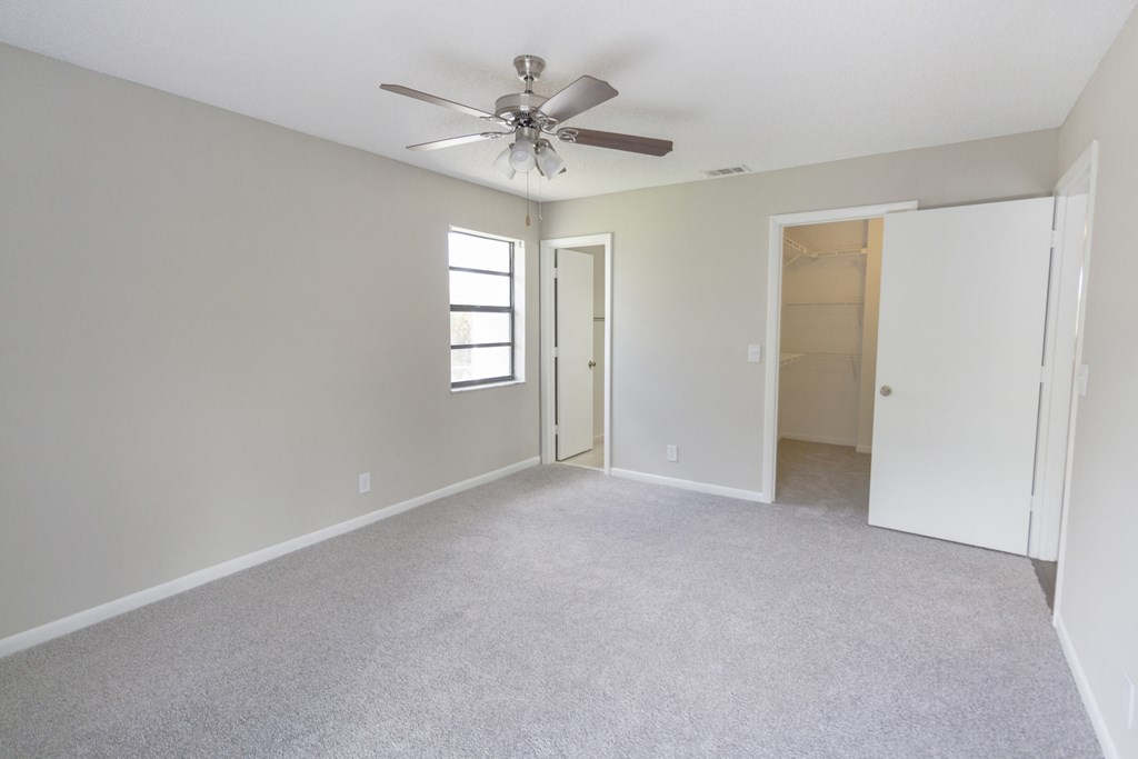A room with a ceiling fan and carpeted floor.